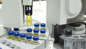 Chromatography vials filled with liquid are being processed on electronic equipment.